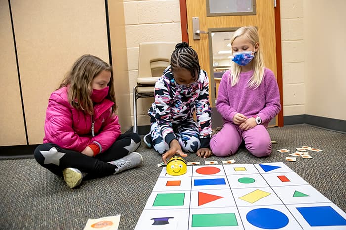 Female CCES students program a BeeBot and make it move in a pattern.