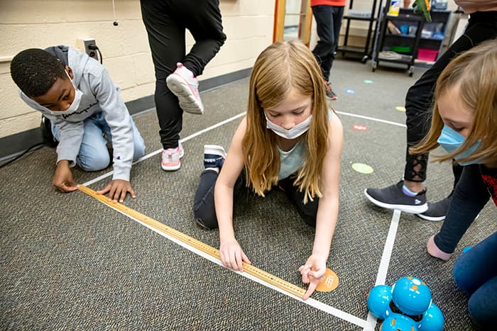 CCES students measuring the distance traveled by a robot during the Hour of Code.