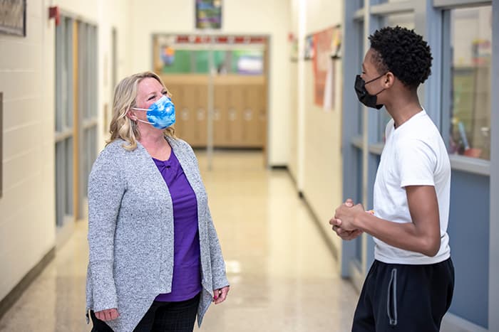 MWMS school counselor Susan Bradley speaks with a male student in a hallway.