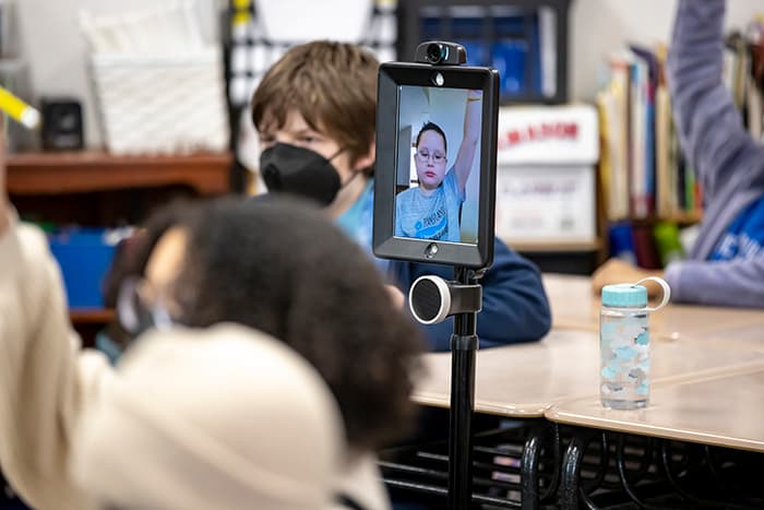 EMMS student Dylan raises his hand via his home and hospital robot, which allows him to attend class virtually.