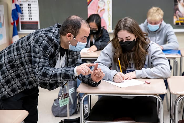 Intern Marcus Virella works with a female student on an in-class activity.