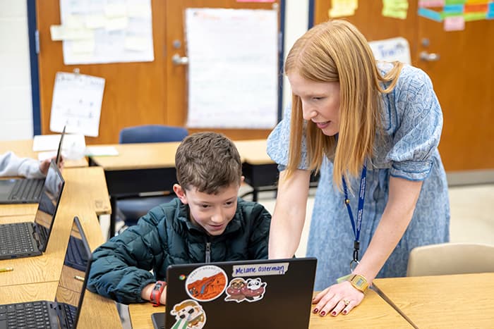 BBES math interventionist Kate Sandoval works with a male student on a computer.