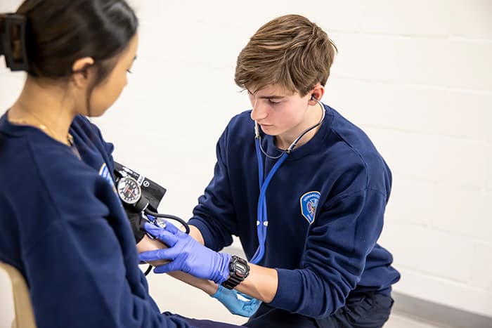 EMT student Ben Gallagher takes his fellow student's blood pressure.