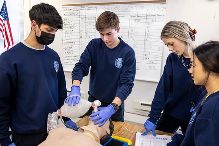 EMT student Ben Gallagher and his classmates practice providing oxygen to a mannequin.