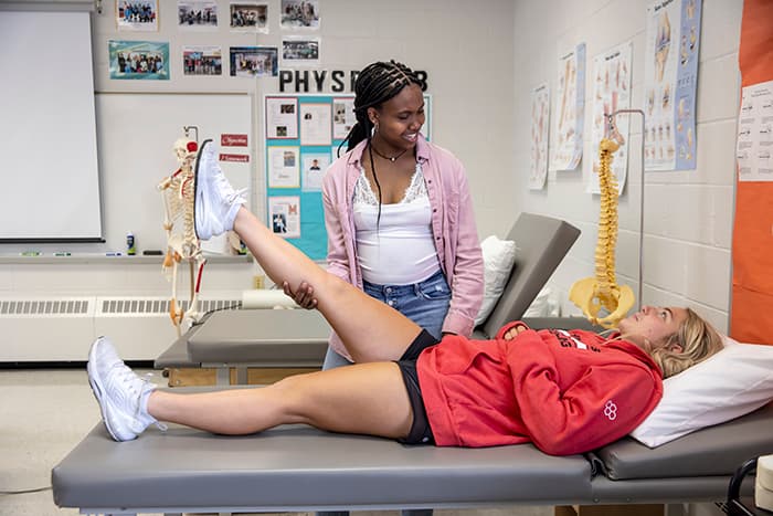 Physical rehabilitation student Mia Swaby-Rowe helps her fellow student extend her leg.