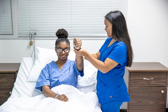 CNA student Kelly Song checking a female patient's mobility.