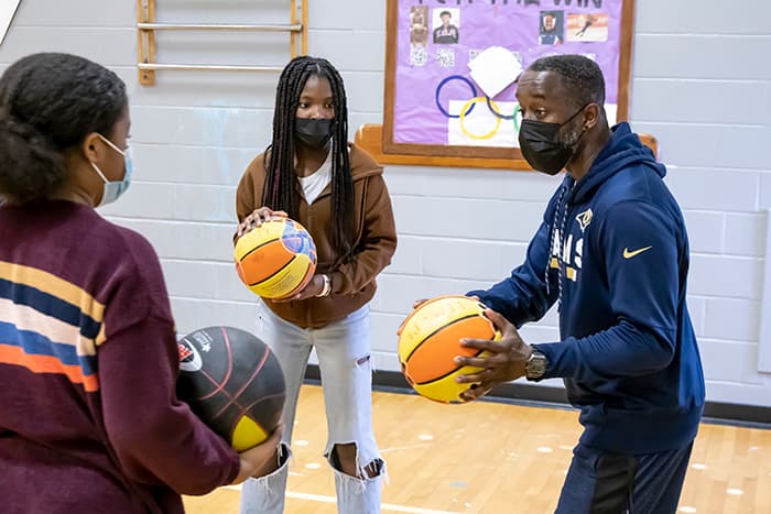 Jason Fahie shows students how to hold a basketball.