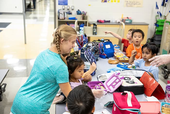 Catherine Gilbert helping students open lunch boxes in the WAVES cafeteria.