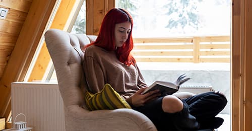 A female student sitting in an armchair and reading.