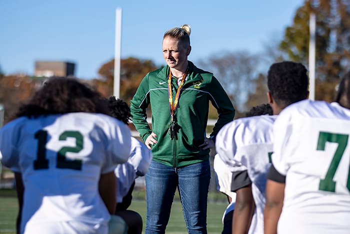Chantal Thacker stands in front of WLHS JV football players.
