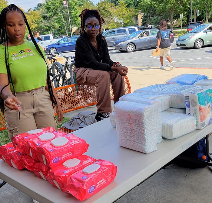 Students organizing a table of diapers and wipes at the OMHS food pantry