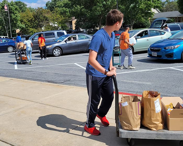 Students delivering food to cars.
