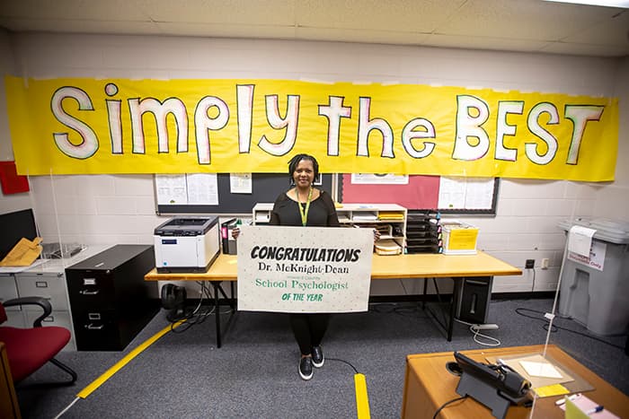 Dr. Chandra McKnight-Dean with 'simply the best' sign behind her.