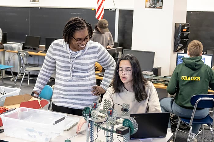 Wilde Lake High School Project Lead the Way teacher Cara Roberts works with a student to construct their automated assembly line.