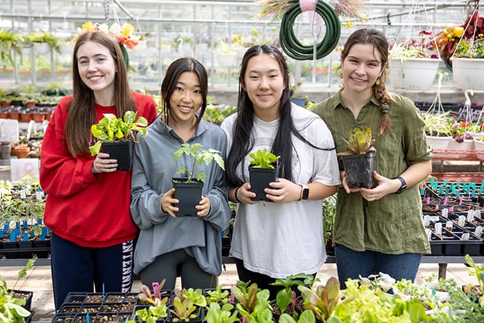 A group of girls holding potted plants.