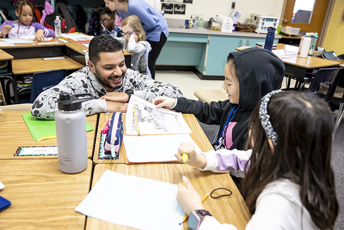 Irfan Dean kneeling and working with a group of students.