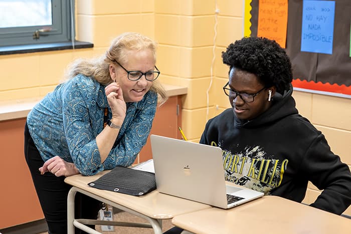 Pamela Paris works with a male student on a computer.