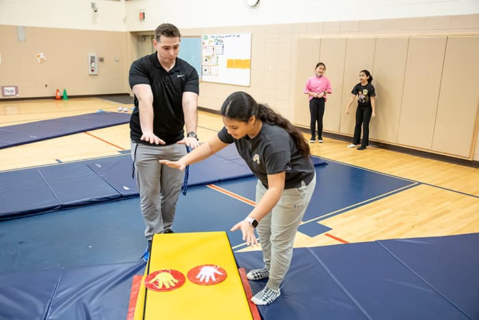 William Perez shows a student how to hold her arms straight.