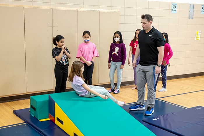 William Perez teaching a group of students in a gym class.