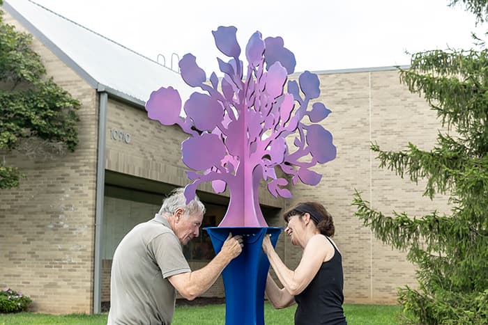 Two people working to set up The Evening Blooms sculpture.