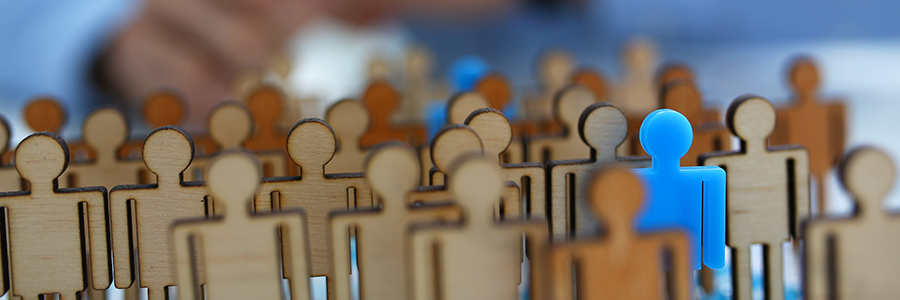 executive search concept of wooden figures. one in blue stands out.