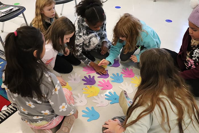 DRES students sitting on the floor doing an activity with handprints.