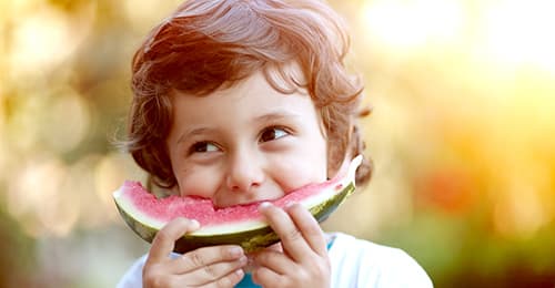 A child eating a slice of watermelon.