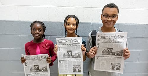 BSAP Summer Institute students hold the newspaper they wrote.