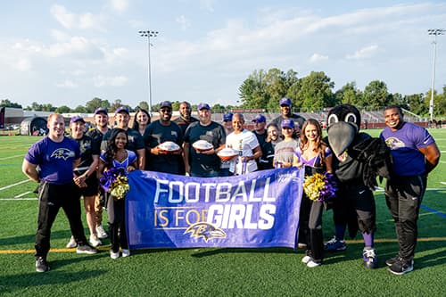 A group on a football field holding a sign saying 
