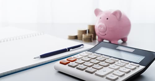 A calculator, pen, paper, a piggy bank and change.