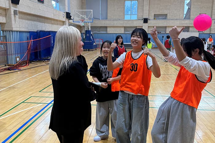 Jen Robinson in a gym with South Korean students wearing jerseys.