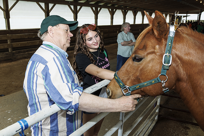 A student and a man petting a horse.