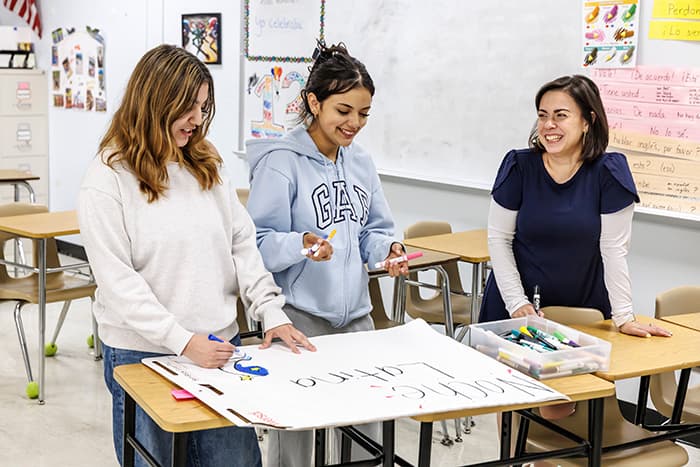 Patricia Zillmer works with two HoHS students on an event poster.