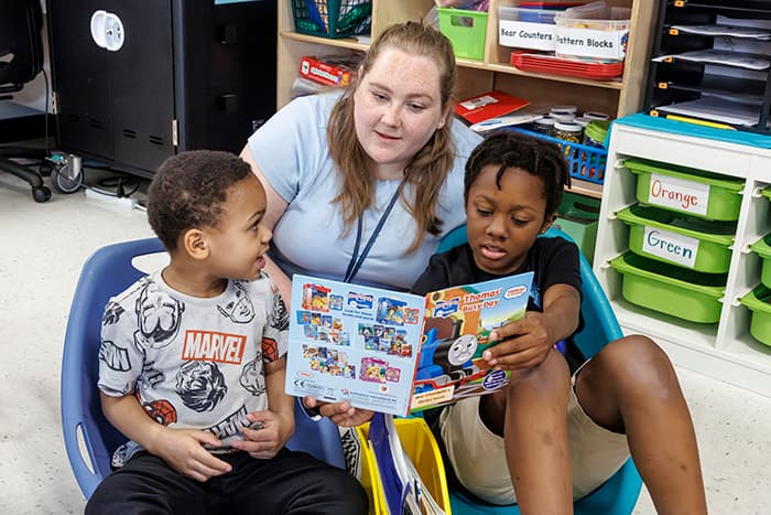 Sam Pickett works with two CRES Bulldog Buddies as they read together.