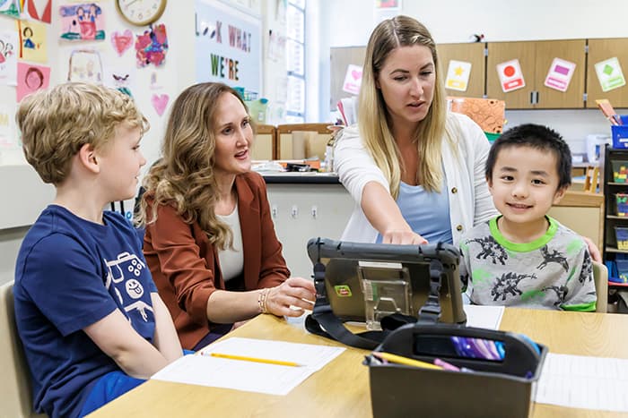 Two special ed staffpeople working with a student using assistive technology.
